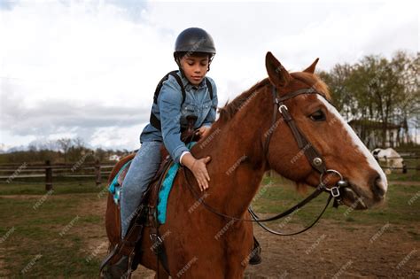 enfant apprenant à monter à cheval avec un casque