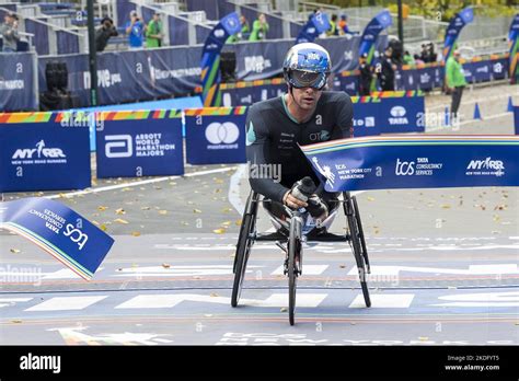 Groupe de coureurs franchissant une ligne d'arrivée, certains encourageant un participant en fauteuil