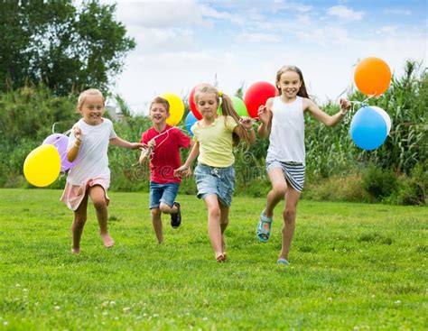 Enfants courant dans un parc, certains tenant des ballons