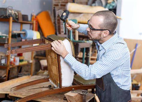 Artisan tapissier travaillant sur un fauteuil ancien