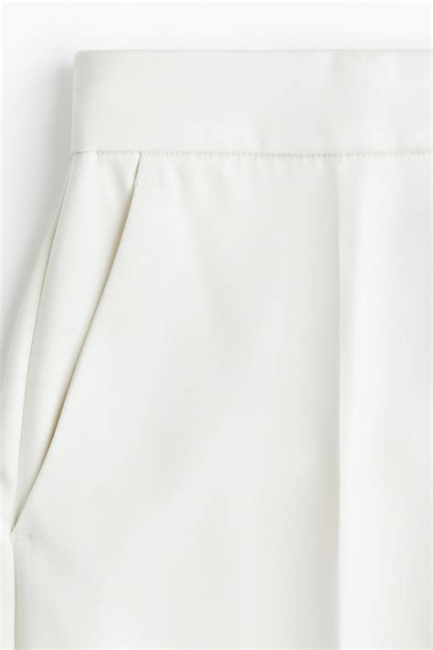 Détail d'un pantalon blanc HKM avec logo et coutures