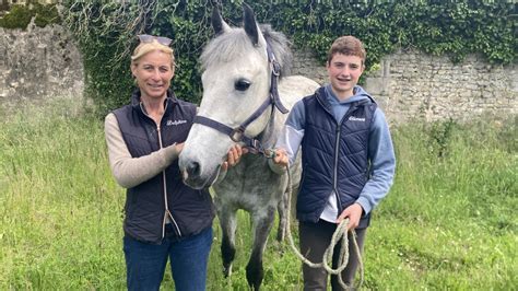 Un instructeur expliquant quelque chose à un jeune cavalier près d'un poney