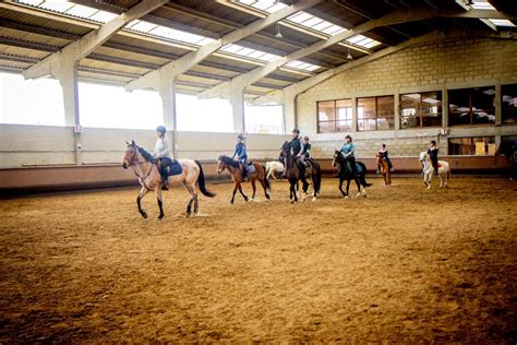 Photo d'un cours d'équitation collectif aux Écuries de la Foux, avec des cavaliers de différents niveaux