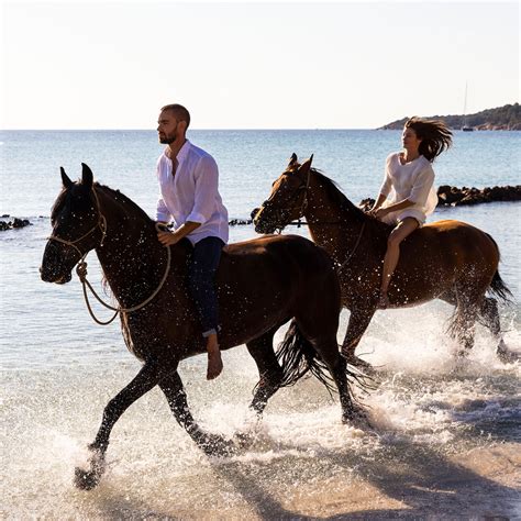 Couple faisant une balade à cheval sur une plage au coucher du soleil