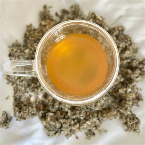 Bol avec des feuilles de framboisier séchées et une tasse de tisane