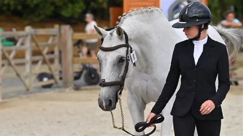 Monitrice expliquant quelque chose à une jeune cavalière devant un cheval
