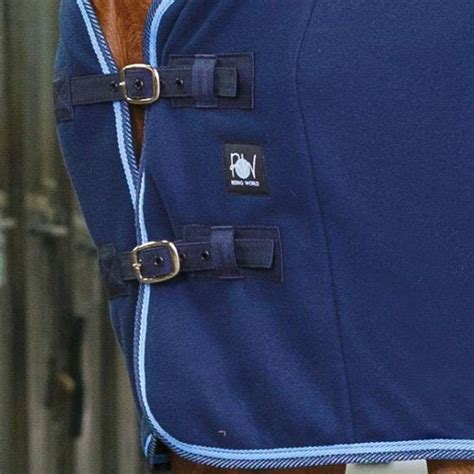 Gros plan sur la bouclerie argentée et les sursangles croisées d'une couverture Horze