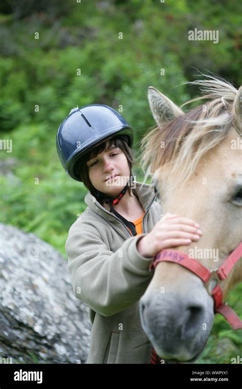 Un jeune enfant souriant caressant un poney