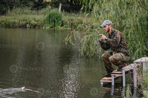 Pêcheur au bord d'une rivière dans un paysage verdoyant
