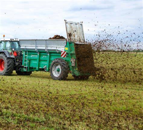 Tracteur avec épandeur de fumier en action